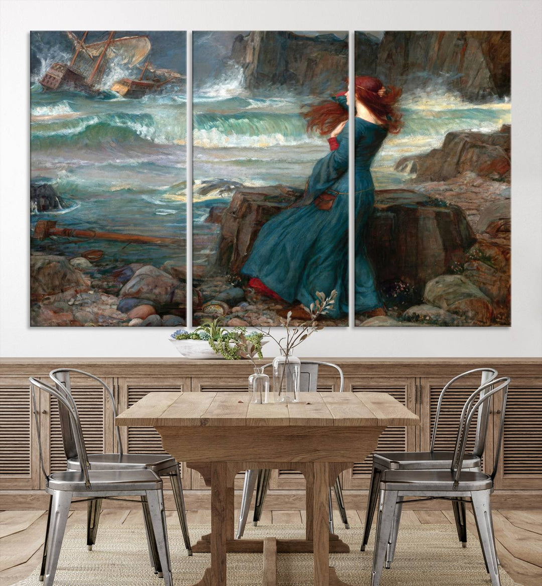 The Miranda by the Shore Wall Art Canvas Print depicts a woman in a blue dress standing by the sea, watching a shipwreck.