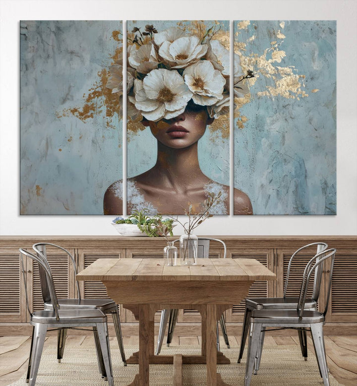 The Golden Petal Silhouette Woman Wall Art Canvas Print, a large 3-panel canvas with a textured gold floral design, serves as a luxurious centerpiece in modern glam settings. The artwork depicts a woman with flowers over her eyes against a textured background and hangs elegantly.