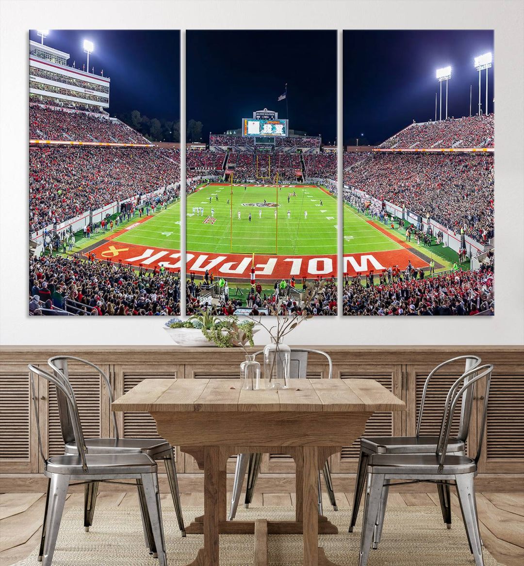 A NC State Wolfpack Football Team print of Carter-Finley Stadium at night features WOLFPACK illuminated brightly in the end zone grass.