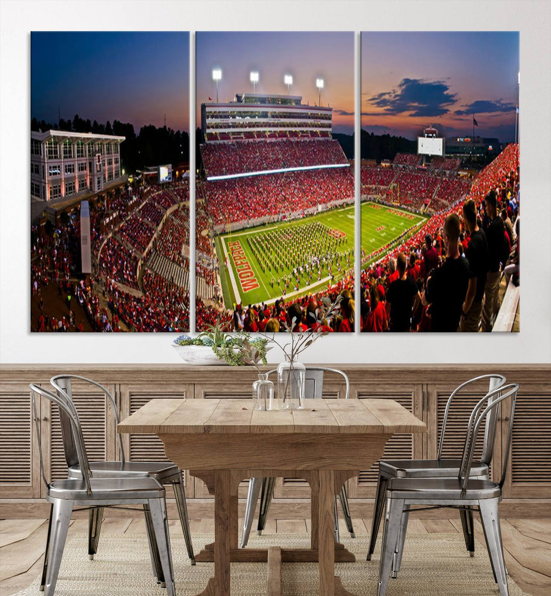 A print of a bustling Carter-Finley Stadium at dusk, featuring fans and a band, captures the essence of NC State Wolfpack football.