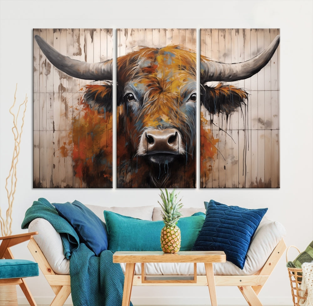 The "Abstract Bull Highland Cow Canvas Wall Art Print," displayed as a three-panel piece, adds vibrant rustic charm to a living room. Its depiction of a large, horned bull beautifully complements the elegance of modern farmhouse decor.