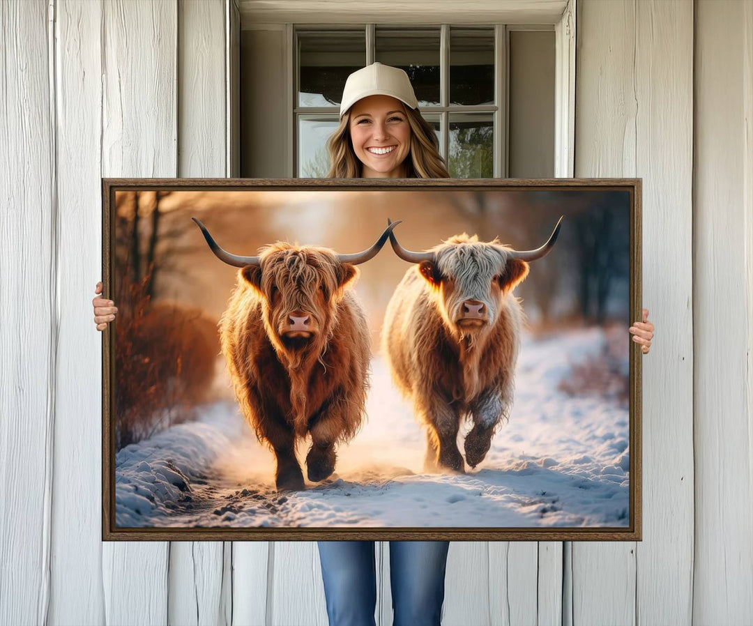 The wall art is a Scottish Highland Cow Horn canvas print featuring cows on a snowy path bathed in warm sunlight, serving as a rustic decor piece.