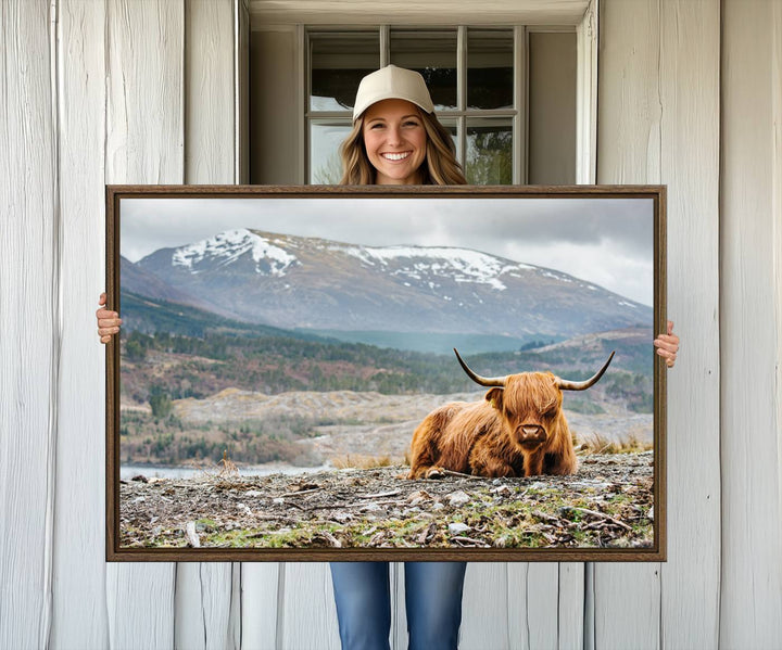 Highland Cow Horn Farm Wall Art Canvas Print is displayed against a wooden wall featuring a mountainous backdrop.