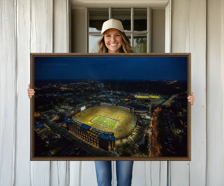 Aerial view of Michigan Stadium at night, surrounded by city lights, depicted on a Michigan Wolverines wall art canvas print.