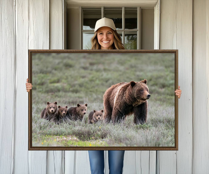 The large canvas print titled "Queen of the Tetons, 399 Grizzly Bear Cubs" showcases majestic wildlife photography of a bear and her cubs walking through the grass. This stunning canvas wall art, handmade in the USA, adds a charming touch to any room with its rustic decor appeal.