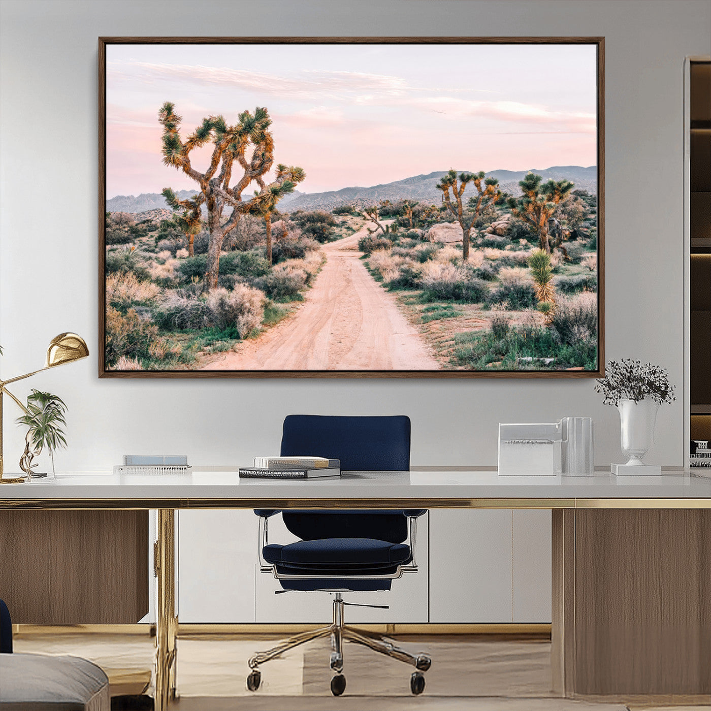 A dusty road winding through Joshua Tree National Park, framed by iconic twisted trees and warm desert tones under a soft pastel sky.