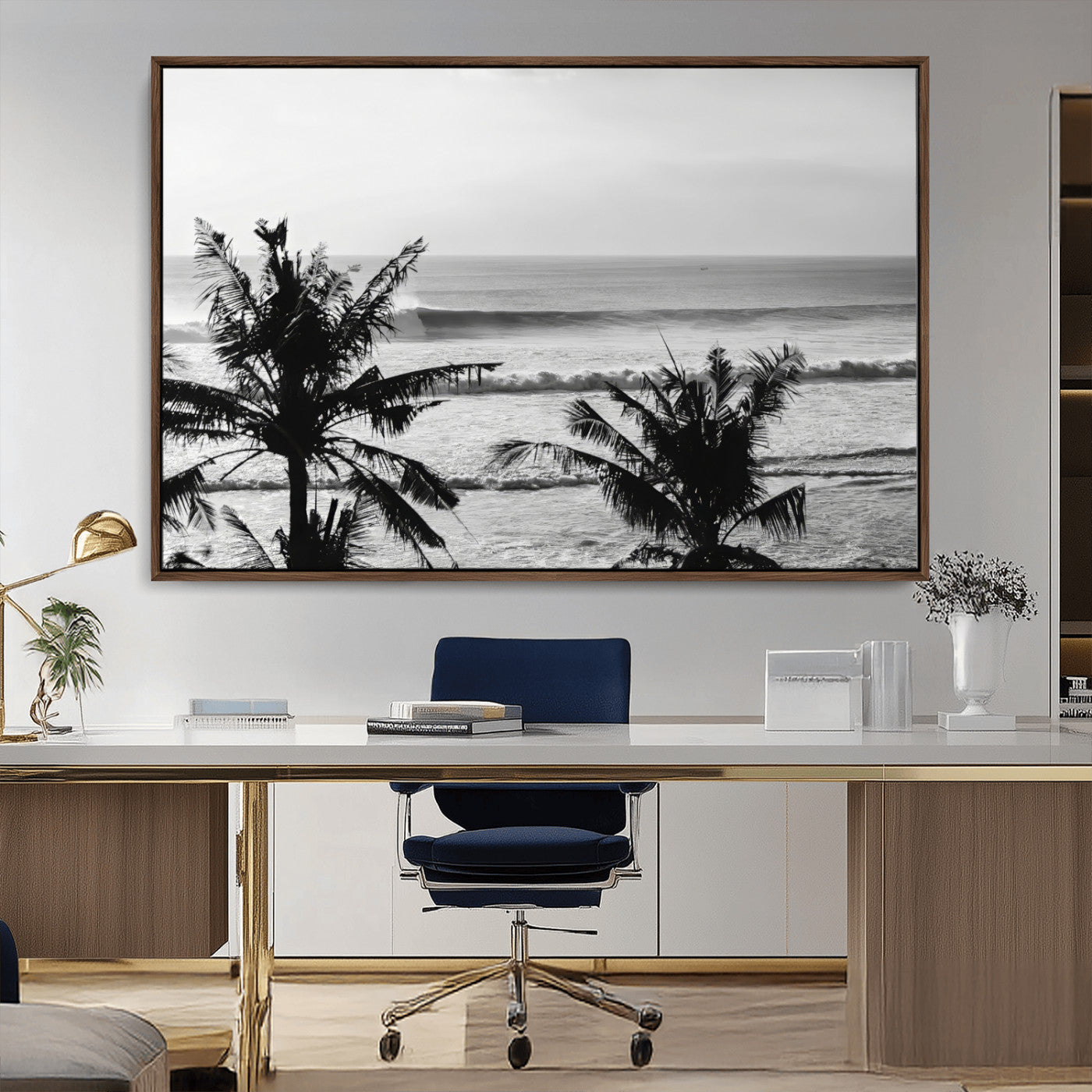 Black and white view of ocean waves crashing on a tropical coastline, framed by silhouetted palm trees under a vast, open sky.