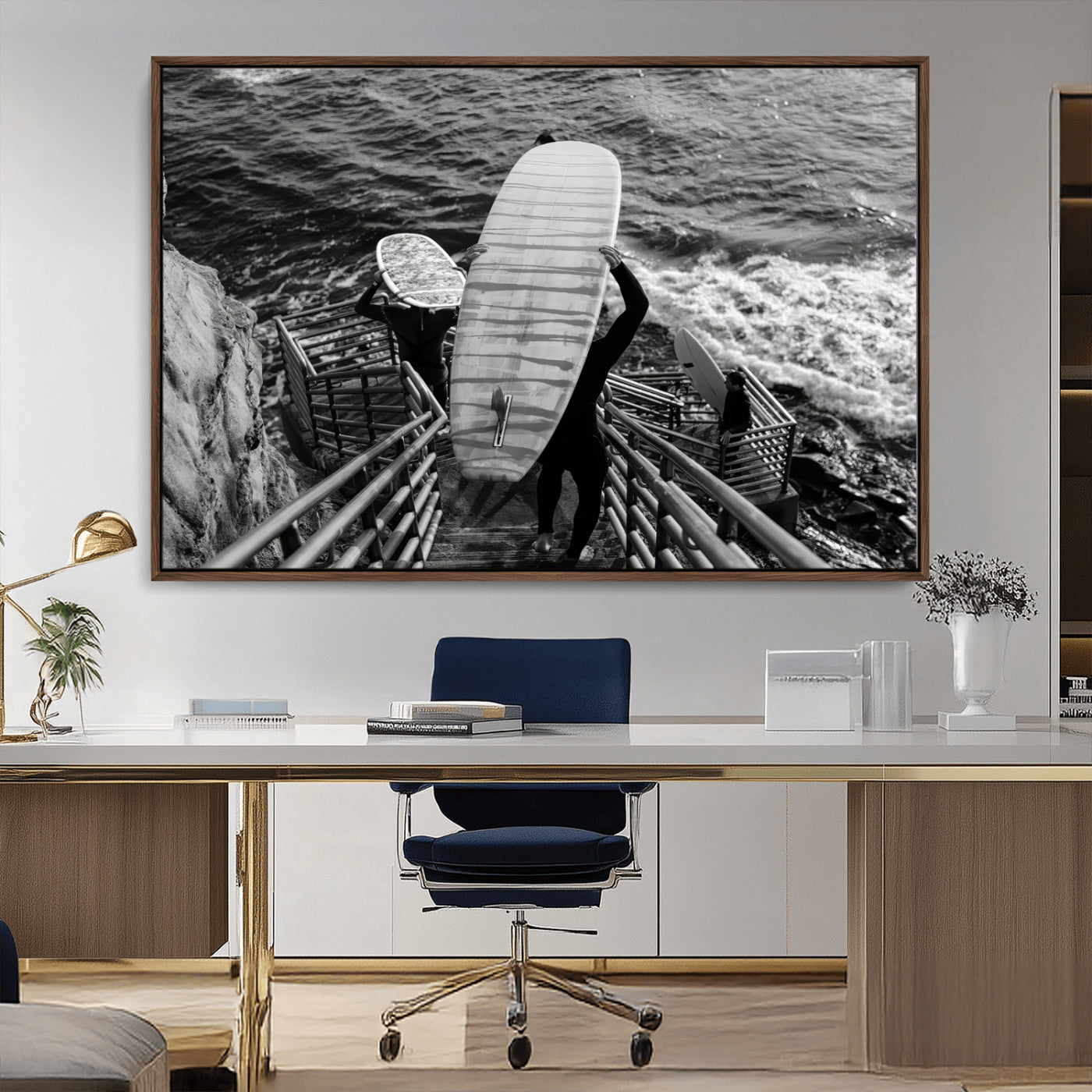 Black and white photo of surfers carrying boards down a rugged cliffside stairway, capturing a bold and adventurous coastal scene.