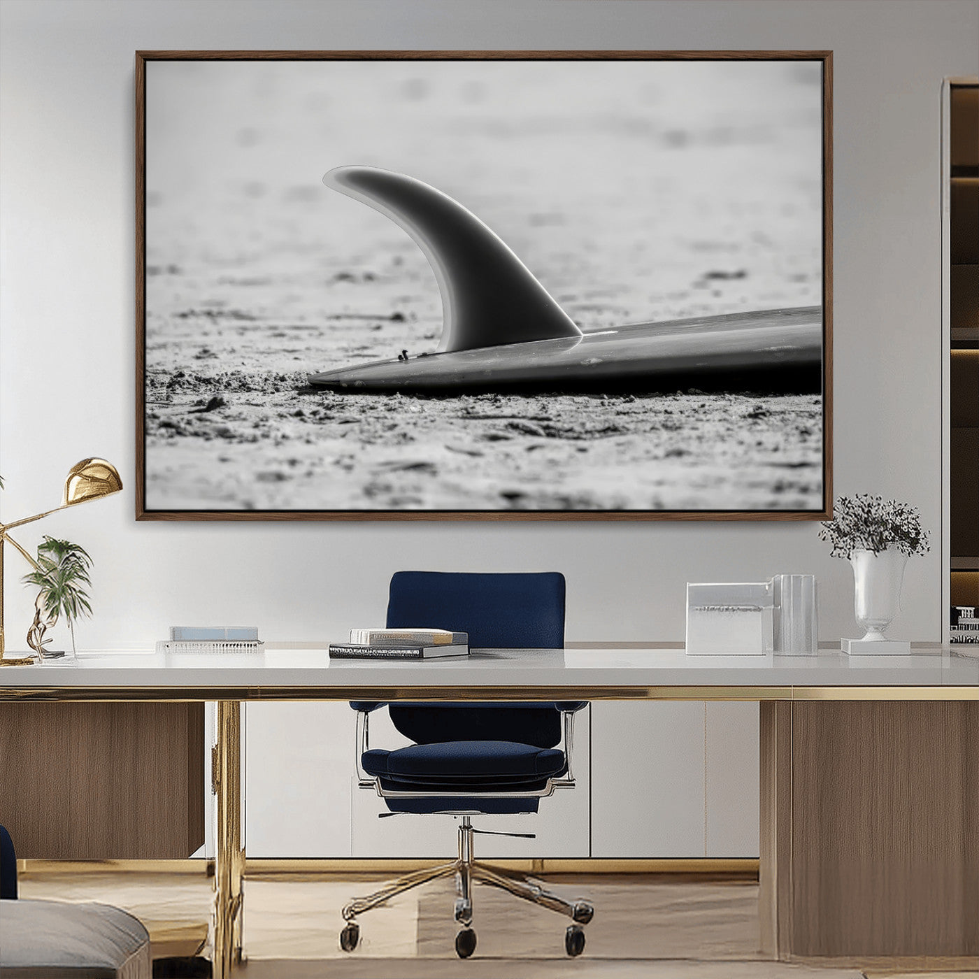 A black and white close-up of a surfboard fin resting on the sandy shore, highlighting minimalist beach aesthetics and classic surf culture.