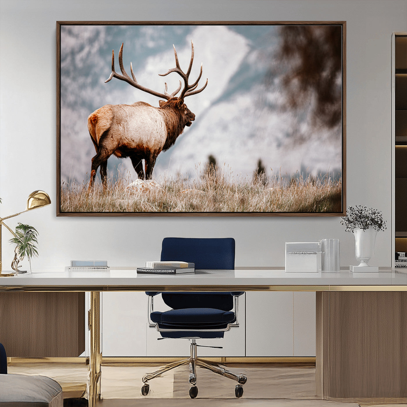 Majestic elk with large antlers standing in grass with snowy mountains in background, perfect for rustic cabin or lodge style decor.