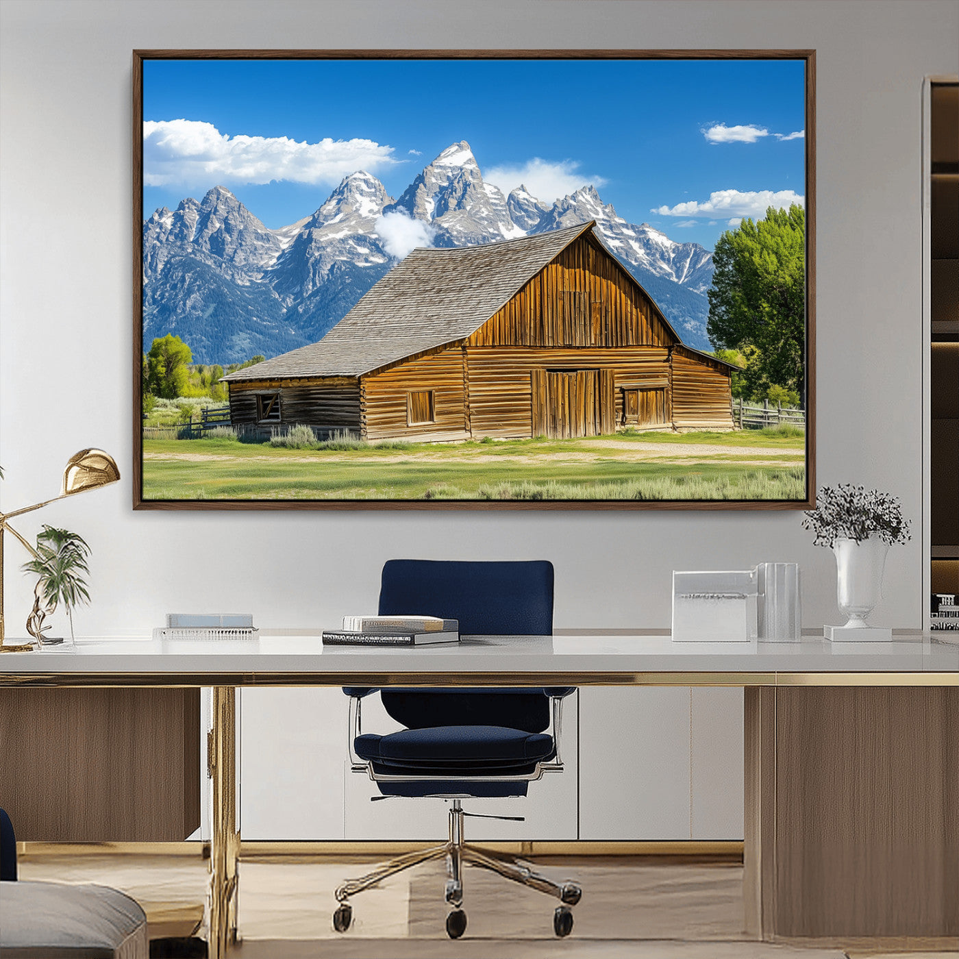 A rustic wooden barn sits in front of towering mountain peaks under a clear blue sky, perfect for farmhouse or cabin style interiors.