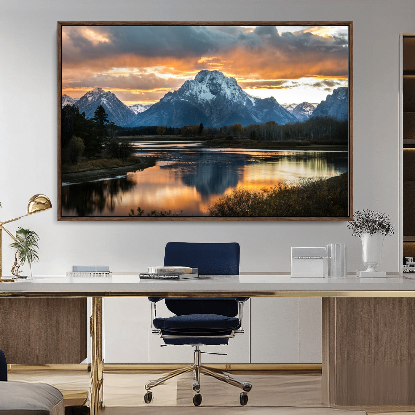 Snow-capped mountains reflecting in a calm lake at sunset, with a dramatic golden sky creating a breathtaking wilderness scene.