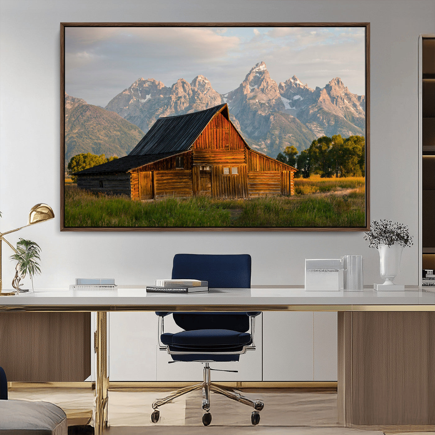Rustic wooden barn set against towering mountain peaks under warm golden light, creating a peaceful Western countryside scene.