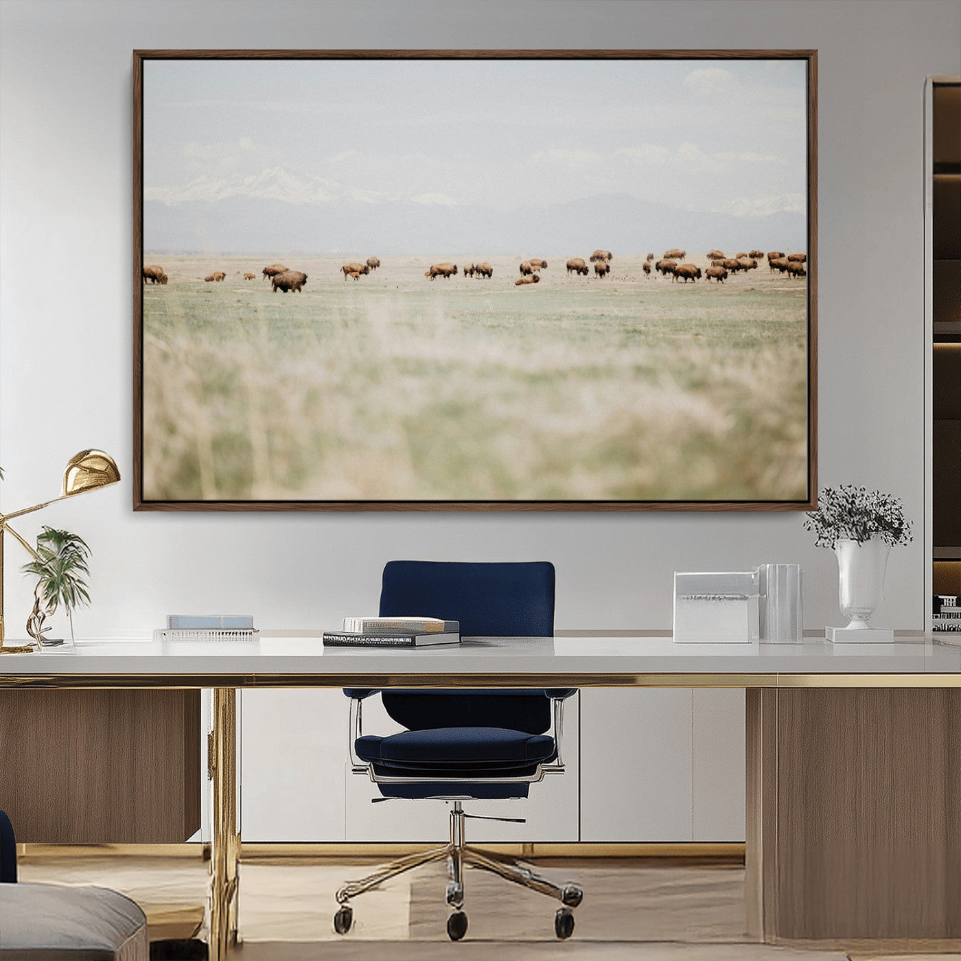 A herd of bison grazing in an open prairie with distant mountains under a soft sky, creating a serene and rustic Western landscape.