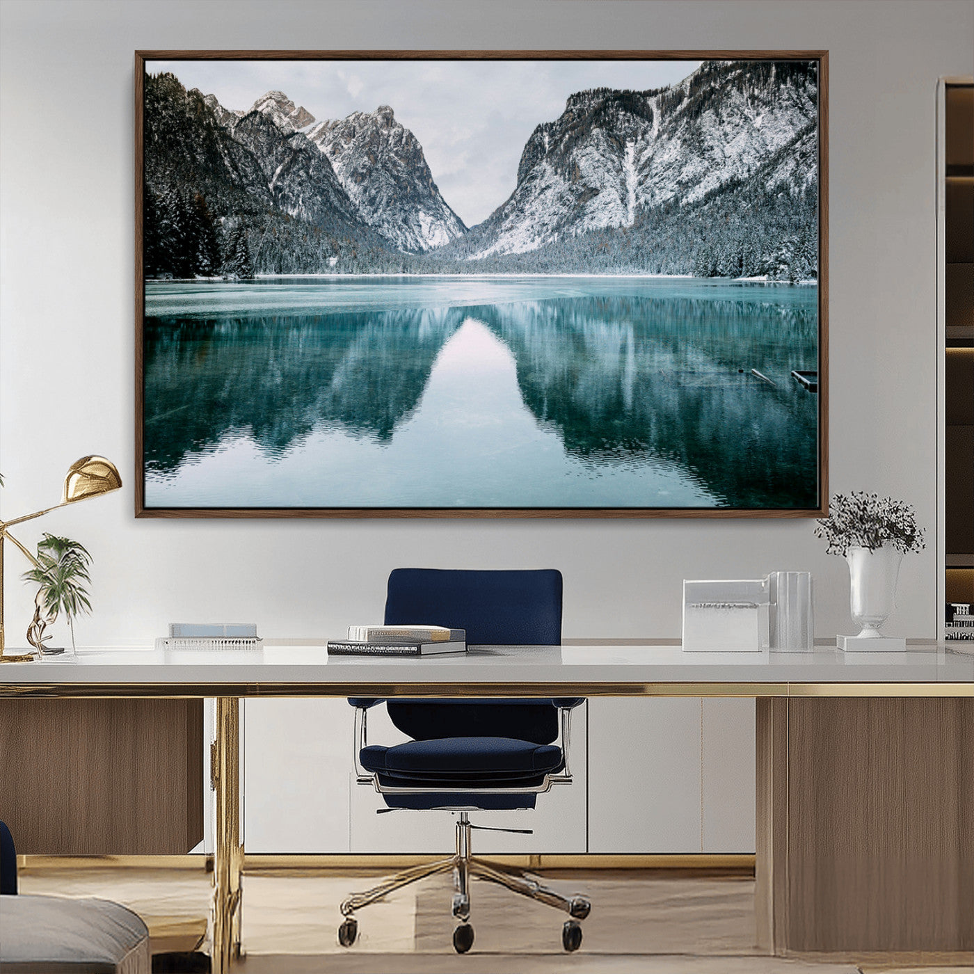 Crystal-clear alpine lake reflecting snow-covered mountains, surrounded by evergreen trees, creating a serene and tranquil winter landscape.