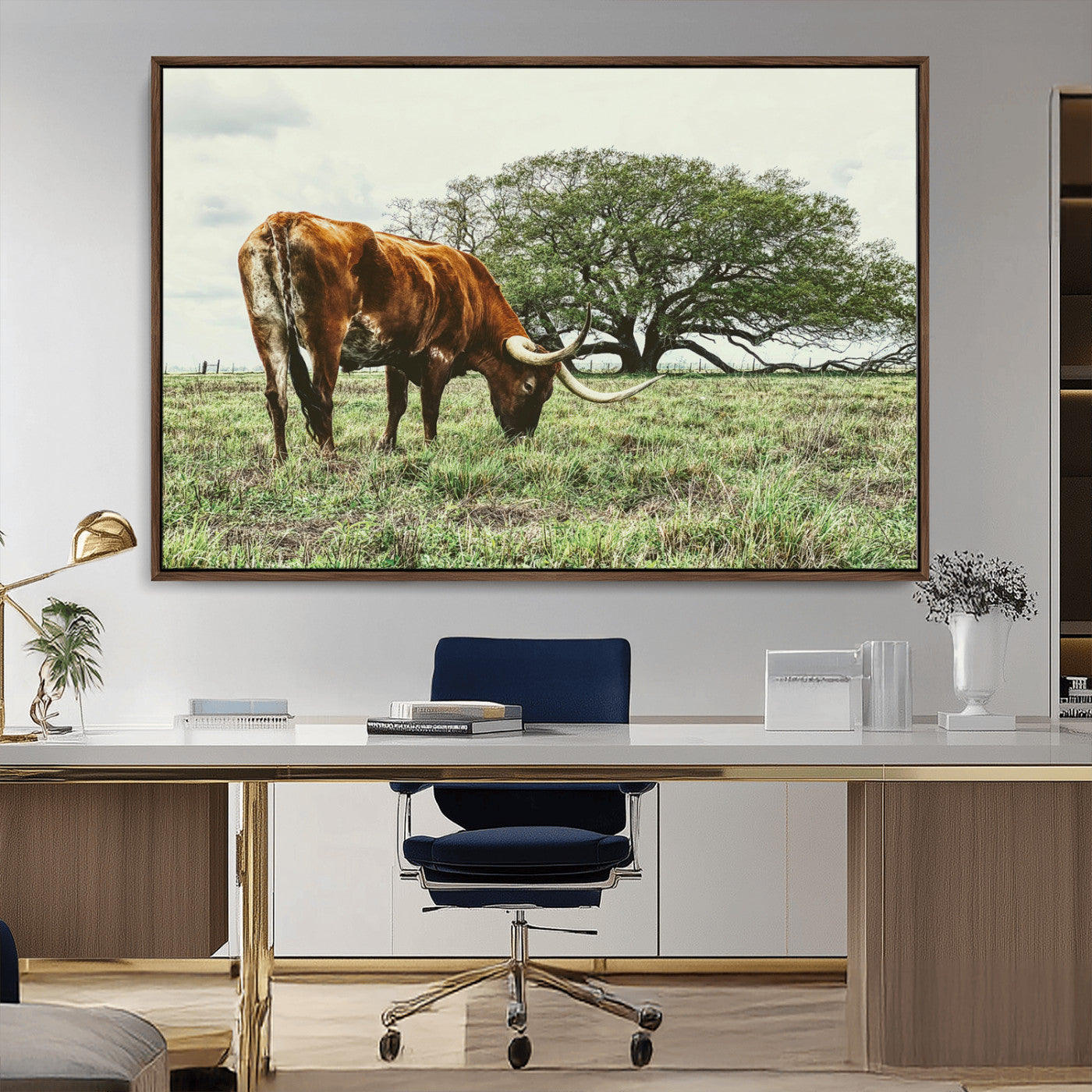 A Texas Longhorn grazing in a green pasture with a large tree in the background, evoking a rustic Western and farmhouse aesthetic.