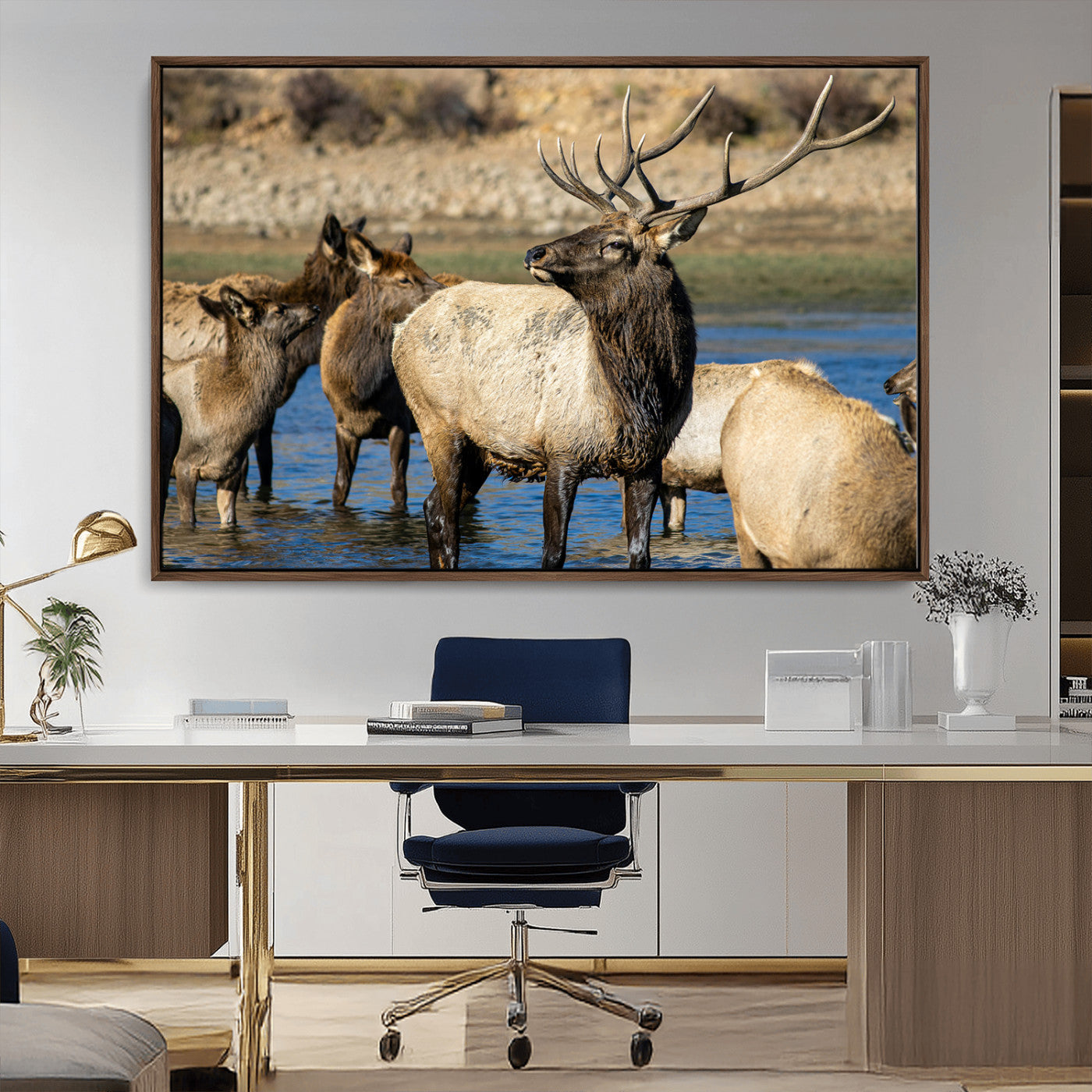 Group of elk standing in shallow water with dry rocky terrain in the background, showcasing wildlife in a natural setting for rustic decor.