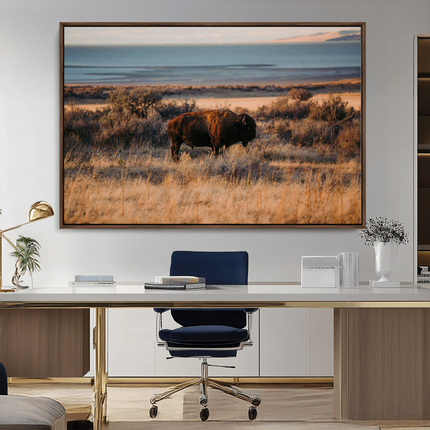 A lone bison grazing in golden prairie grass at sunset, with warm earthy tones and a distant lake view, perfect for rustic and western decor.