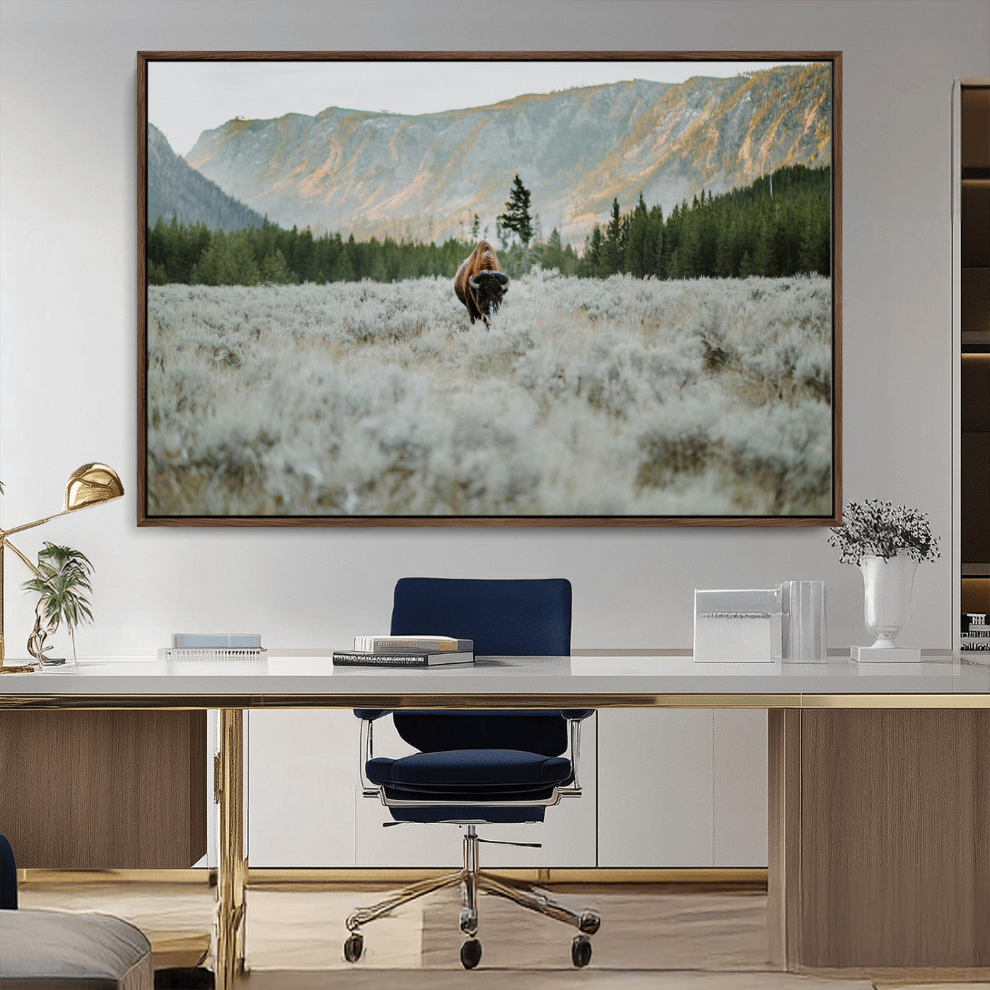 Lone bison standing in a frosted sagebrush field with a pine forest and rugged mountain range in the background under soft morning light – Wall Art Canvas Print.
