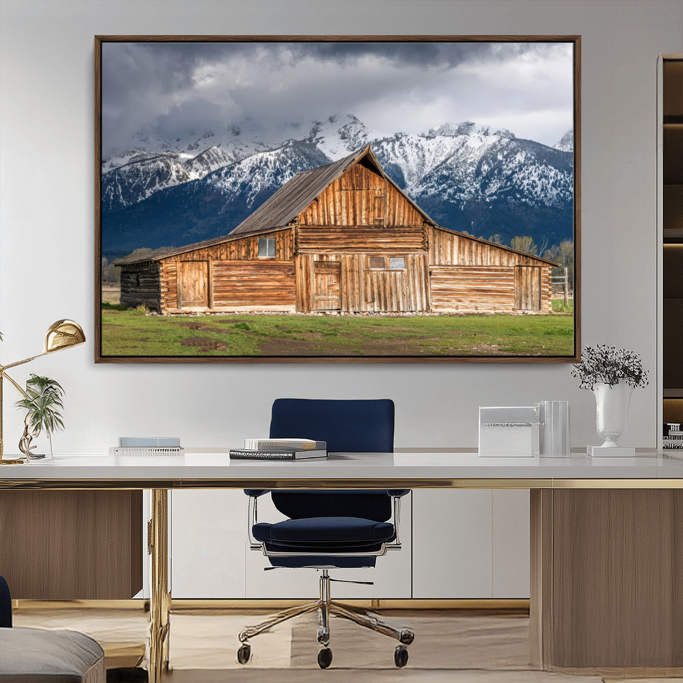 A stunning wall art canvas print featuring a rustic wooden barn set against a backdrop of snow-capped mountains under a dramatic cloudy sky, perfect for adding a touch of rural charm to any space.