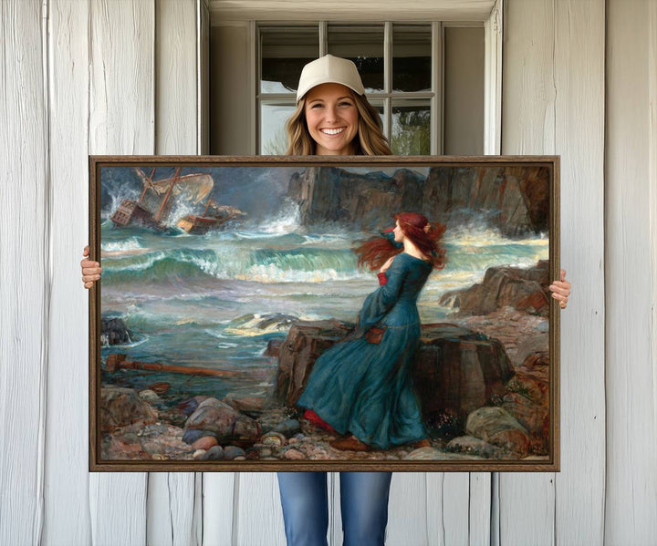 The Miranda by the Shore Wall Art Canvas Print depicts a woman in a blue dress standing by the sea, watching a shipwreck.