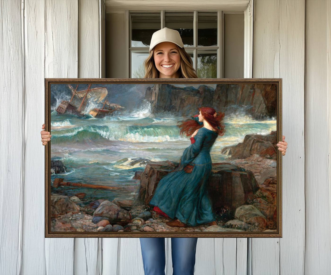 Miranda - The Tempest Canvas Print depicts a woman in a blue dress gazing at a shipwreck on a rocky shore. The artwork is ready to hang.