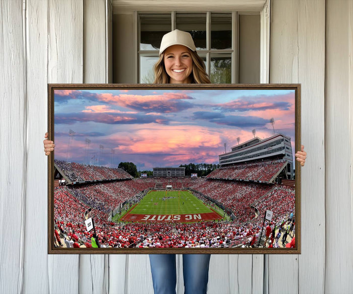 The wall art captures an NC State Wolfpack game under a vibrant sunset on triple canvas.