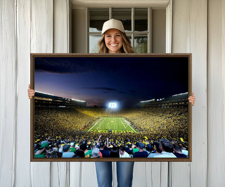 The wall art features a glowing M in this Michigan Wolverines Football Team Ann Arbor Stadium Canvas Print.