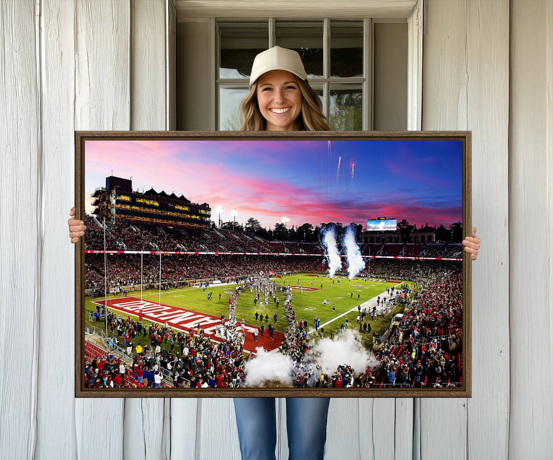 The wall art features a canvas print of the Stanford Cardinal football team, capturing players, fireworks, and smoke against the backdrop of a sunset at Stanford Stadium.