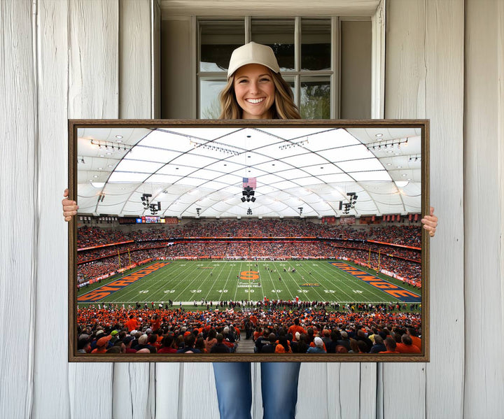 Fans fill the Syracuse JMA Wireless Dome, highlighted in orange and blue under a vaulted roof on this premium canvas print of the scene.