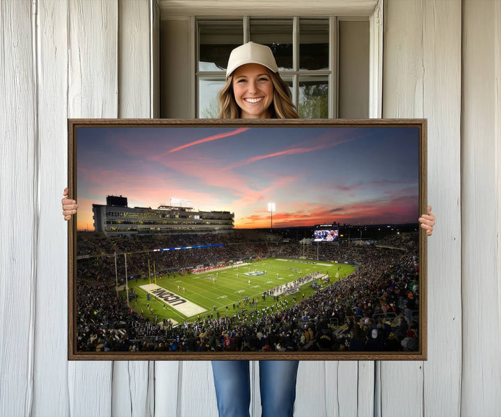 This wall art canvas print captures UCONN Huskies fans energizing a sunset scene at East Hartfords Pratt & Whitney Stadium.