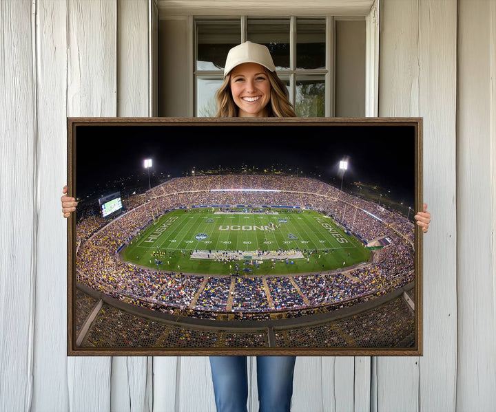 A large football stadium at night, featuring the UCONN Huskies, is depicted on the East Hartford Pratt & Whitney Stadium Wall Art Canvas Print.