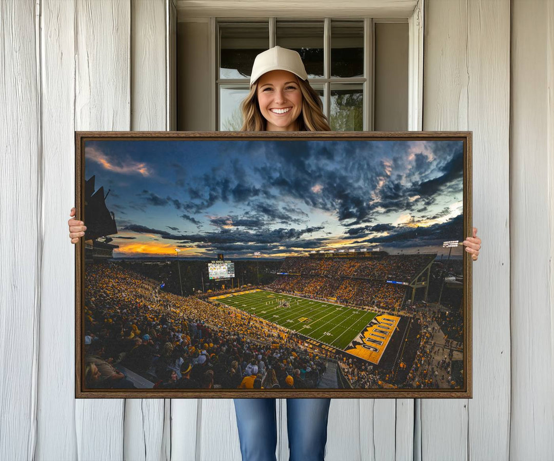 Laramies War Memorial Stadium Print captures a stunning scene of the stadium during sunset, set under a partly cloudy sky illuminated by bright lights.