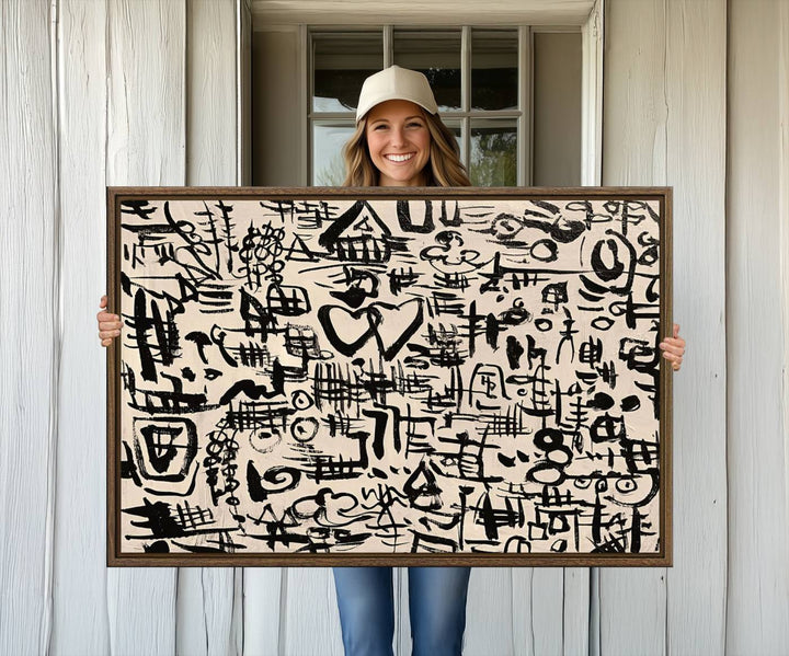 The Abstract Love and Chaos canvas is a museum-quality print featuring black symbols on a beige background, adorned with a heart and scribble design. It is framed to enhance its artistic appeal.