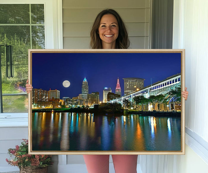 Cleveland City Lights Night Skyline Wall Art canvas showcases a moonlit cityscape reflected on water.