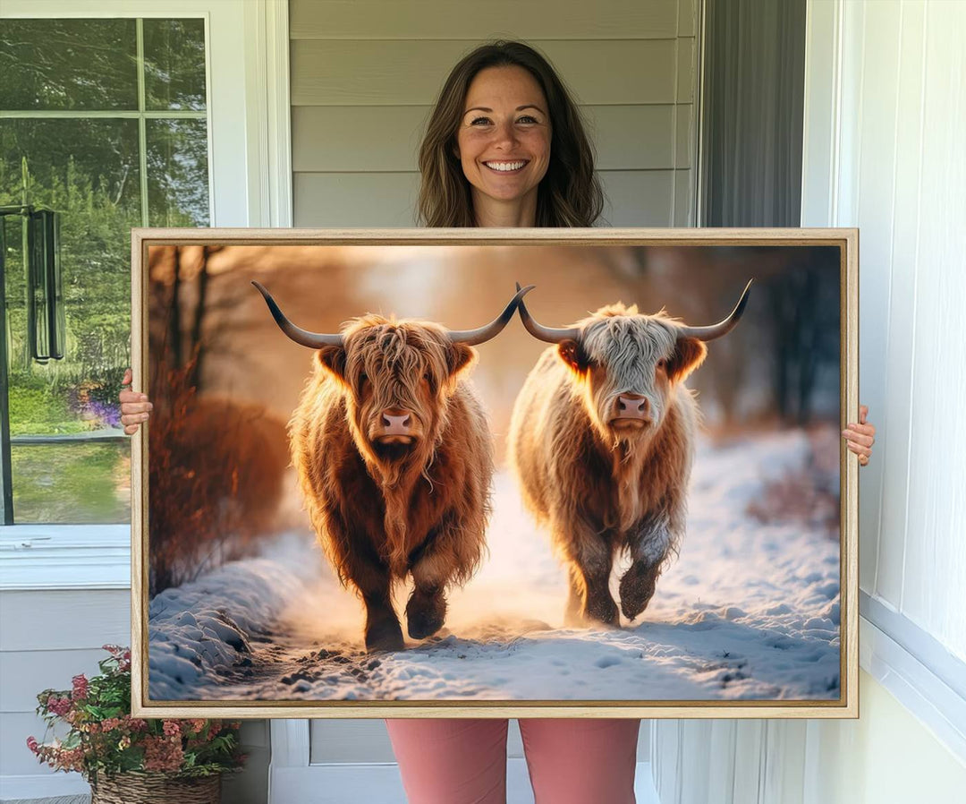 The wall art is a Scottish Highland Cow Horn canvas print featuring cows on a snowy path bathed in warm sunlight, serving as a rustic decor piece.