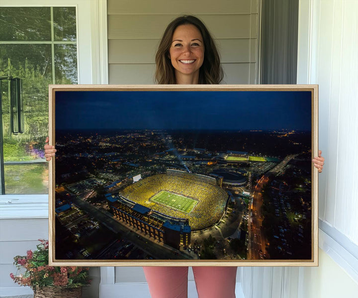 Aerial view of Michigan Stadium at night, surrounded by city lights, depicted on a Michigan Wolverines wall art canvas print.