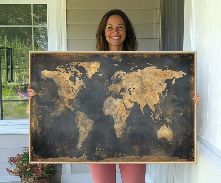 The Grunge World Map Canvas Wall Art features golden tones and is displayed against a white-paneled wall.