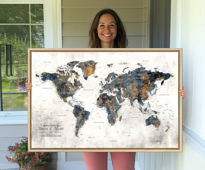 A smiling woman proudly holds the Personalized Push Pin Map Wall Art Print - Detailed Custom World Map Canvas Print in front of a white wall, perfect for travel enthusiasts eager to mark their adventures.