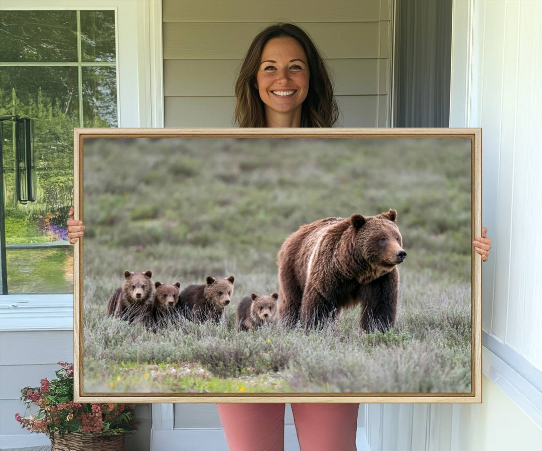 The large canvas print titled "Queen of the Tetons, 399 Grizzly Bear Cubs" showcases majestic wildlife photography of a bear and her cubs walking through the grass. This stunning canvas wall art, handmade in the USA, adds a charming touch to any room with its rustic decor appeal.