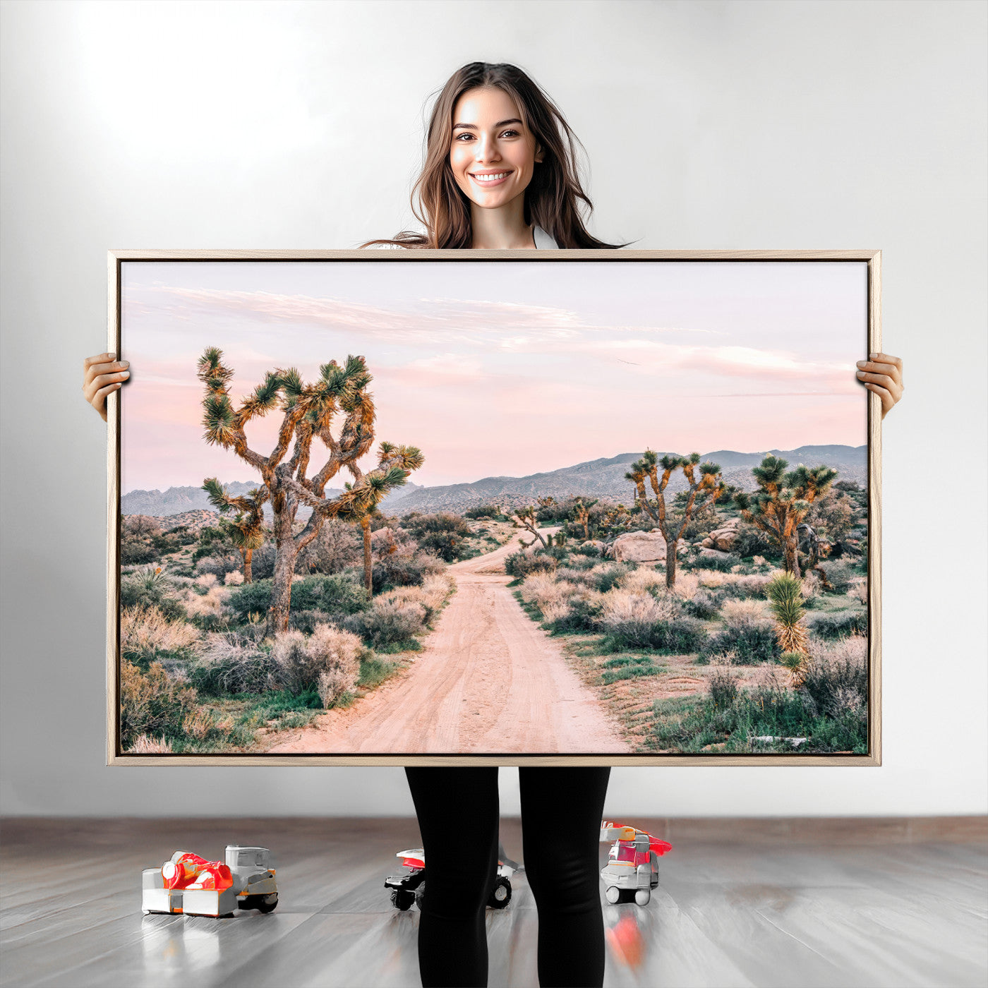 A dusty road winding through Joshua Tree National Park, framed by iconic twisted trees and warm desert tones under a soft pastel sky.