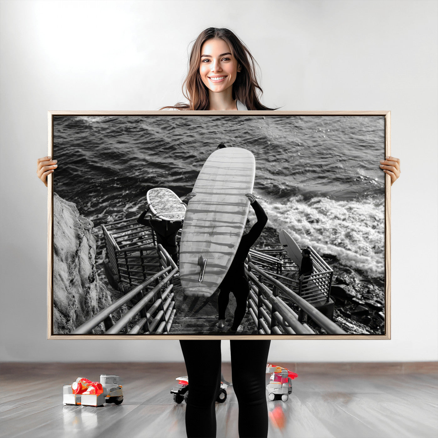 Black and white photo of surfers carrying boards down a rugged cliffside stairway, capturing a bold and adventurous coastal scene.