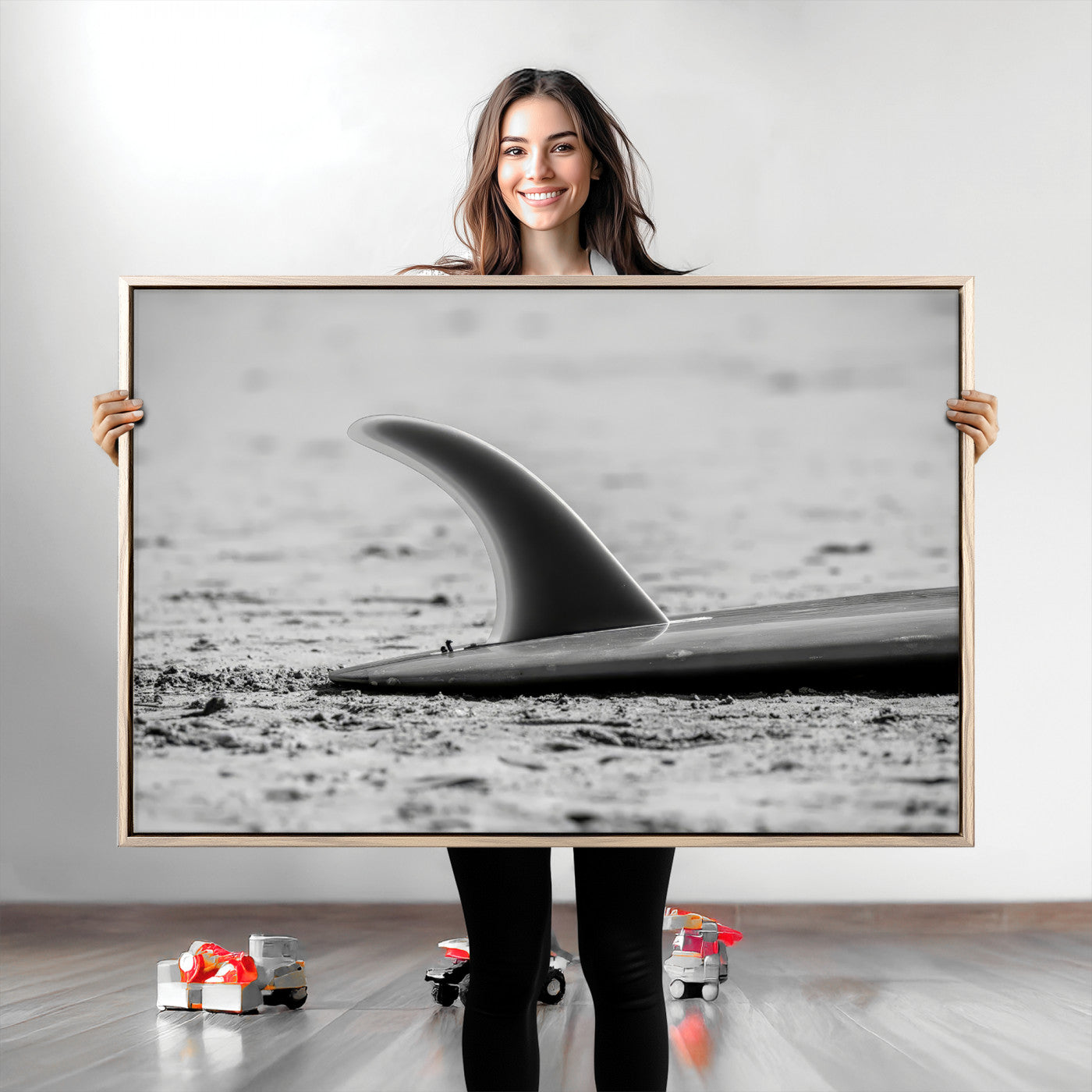 A black and white close-up of a surfboard fin resting on the sandy shore, highlighting minimalist beach aesthetics and classic surf culture.
