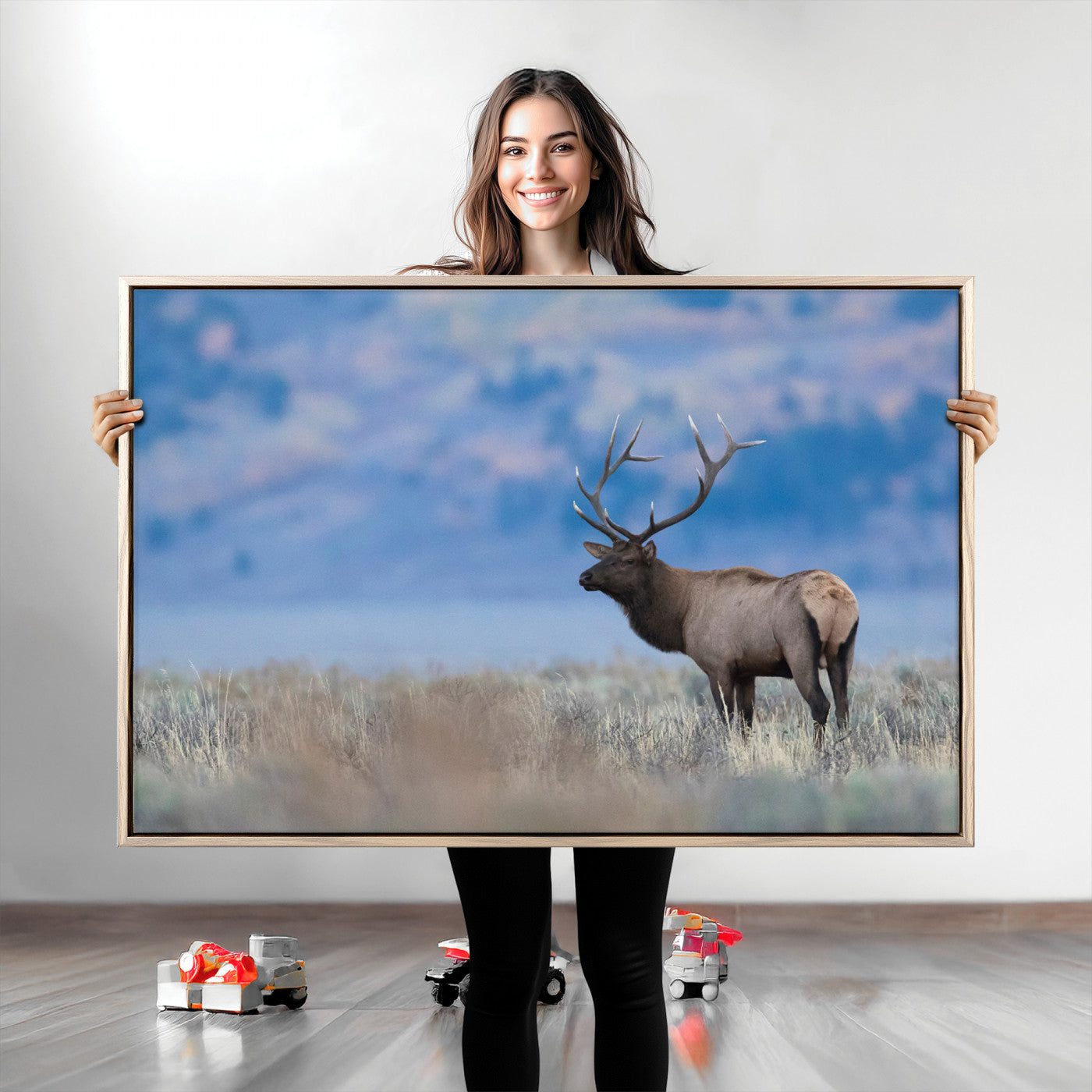 Elk with large antlers standing in open field, mountains blurred in background, perfect for rustic cabin or lodge-style decor.