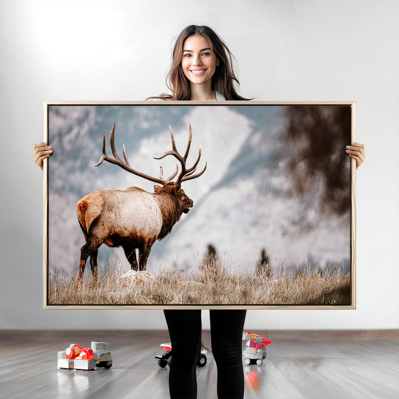 Majestic elk with large antlers standing in grass with snowy mountains in background, perfect for rustic cabin or lodge style decor.