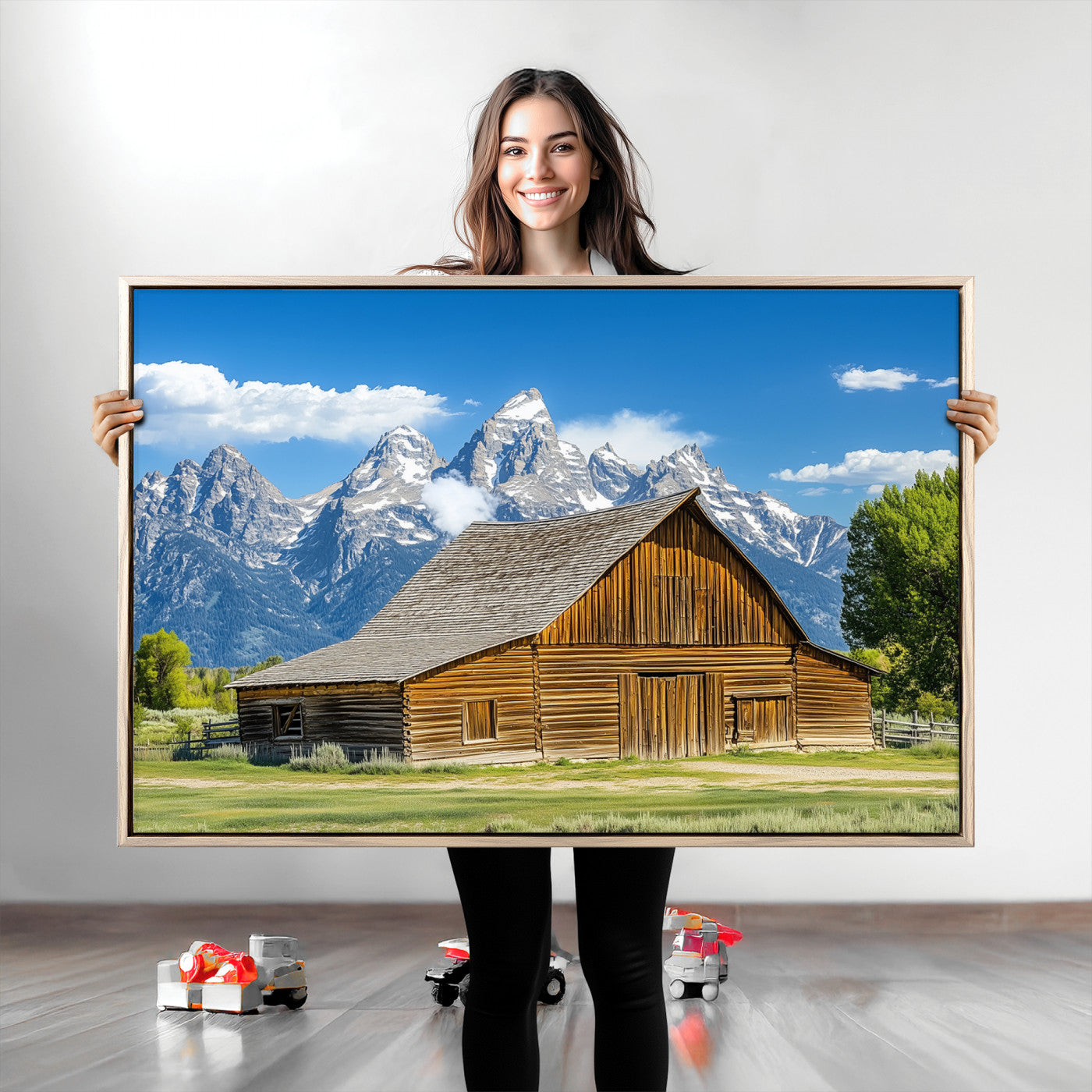 A rustic wooden barn sits in front of towering mountain peaks under a clear blue sky, perfect for farmhouse or cabin style interiors.