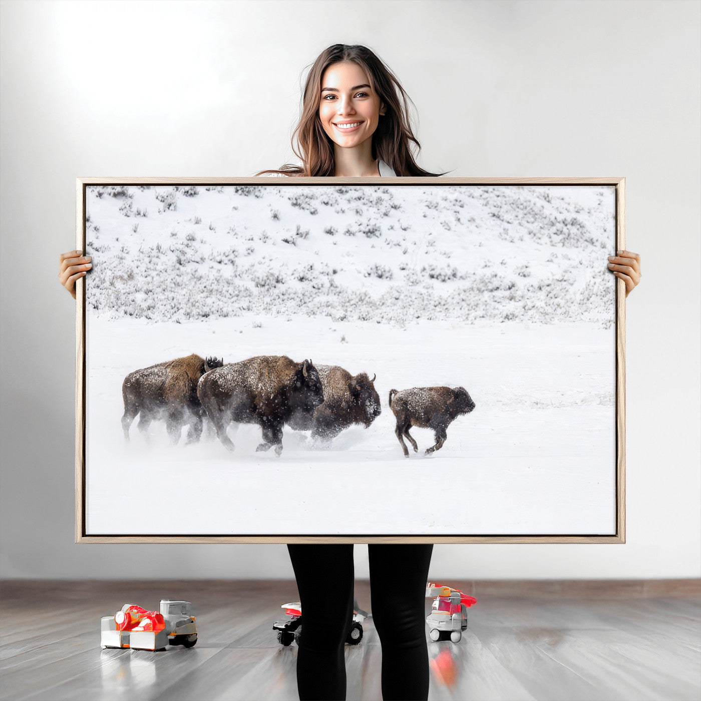 Bison herd running through a snowy open field with mountain backdrop, perfect for rustic or western-themed wall decoration.