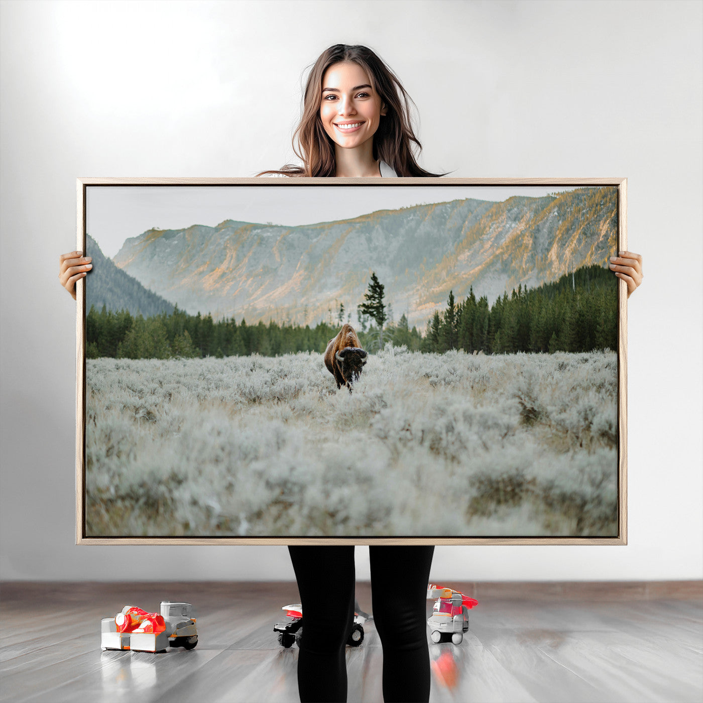 Lone bison standing in a frosted sagebrush field with a pine forest and rugged mountain range in the background under soft morning light – Wall Art Canvas Print.