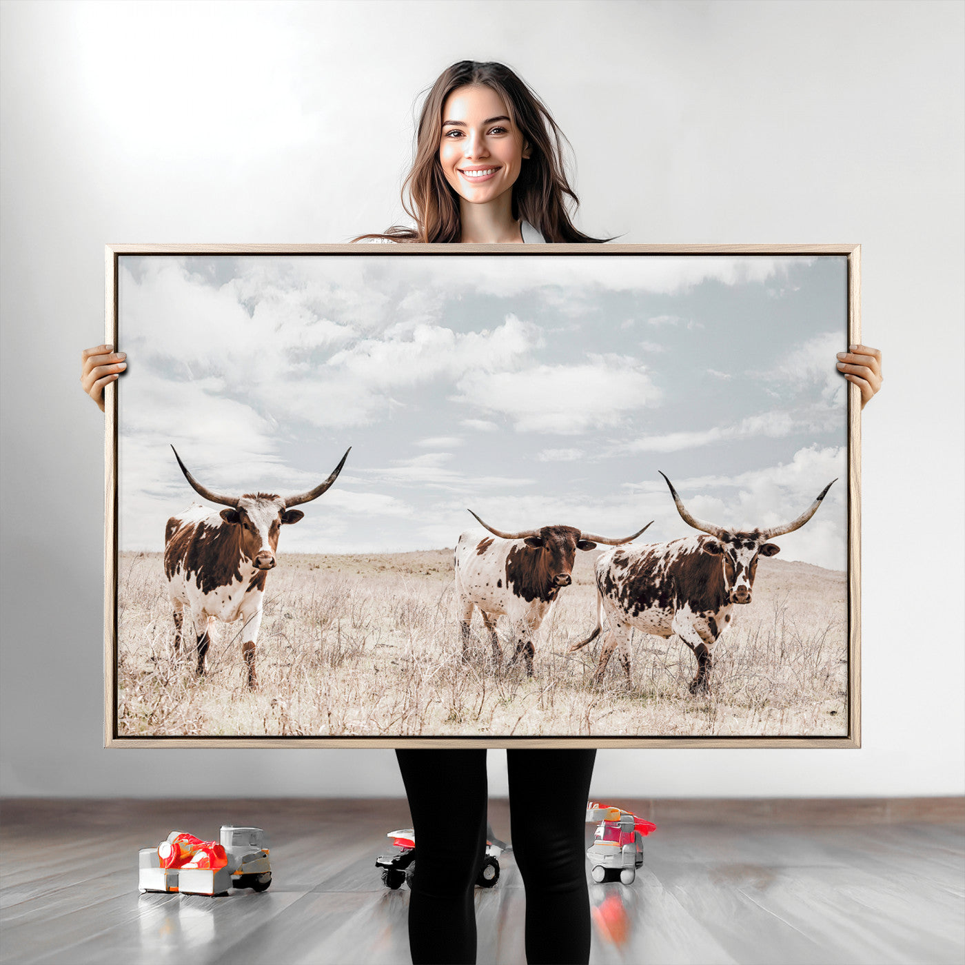 Three Texas Longhorn cattle walking through a dry grassy field under a partly cloudy sky.