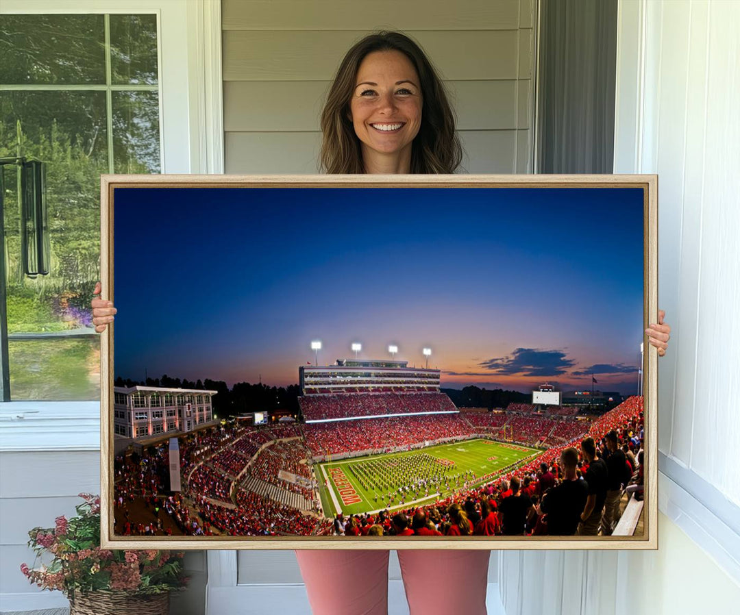 The Wolfpack Football Team Print captures a band and crowd at dusk in a premium canvas art style at Raleigh Carter-Finley Stadium.